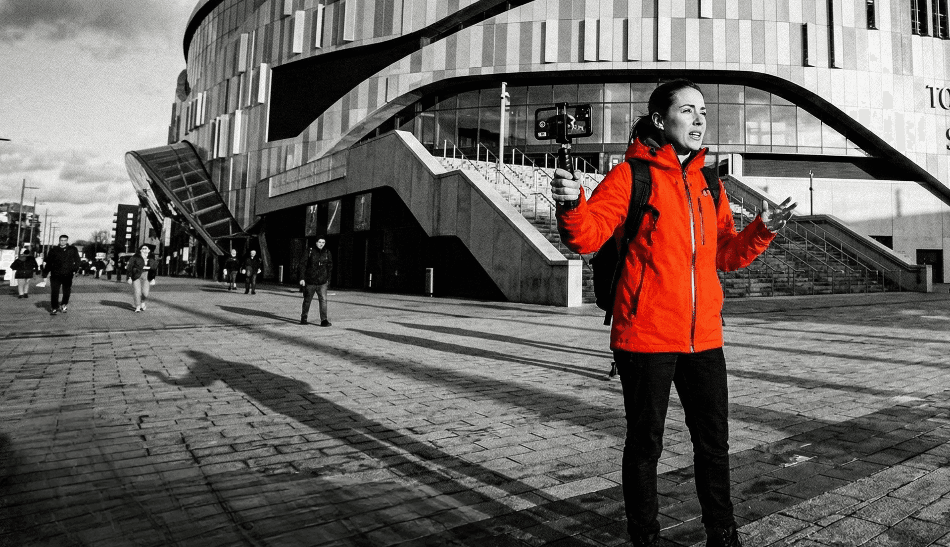 Female creator at a stadium wearing a red jacket