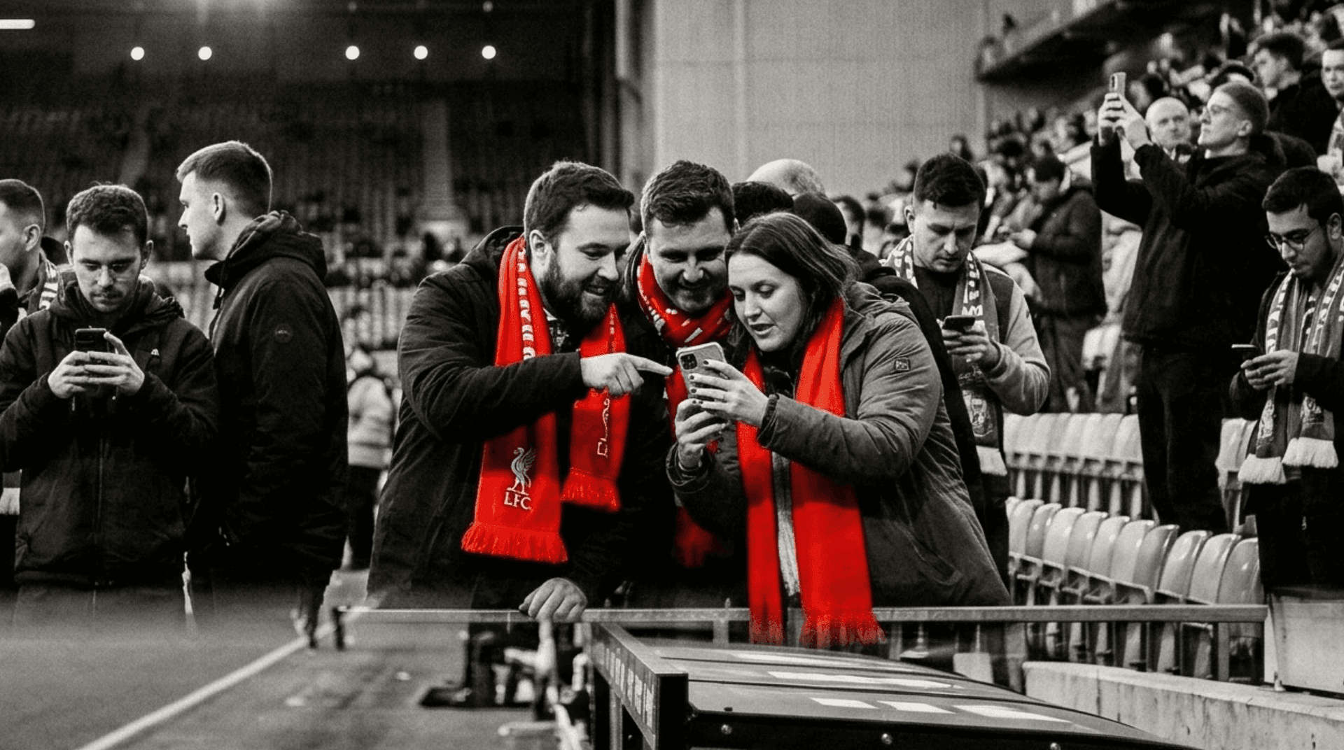 Group of fans in scarves looking at a phone together